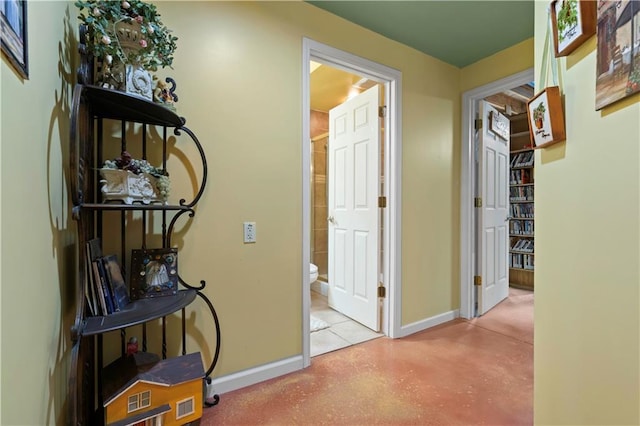 hall featuring baseboards and concrete floors