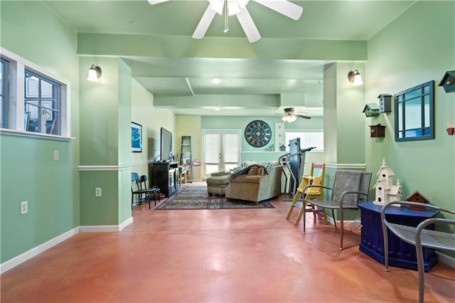 living room featuring ceiling fan, baseboards, and finished concrete flooring