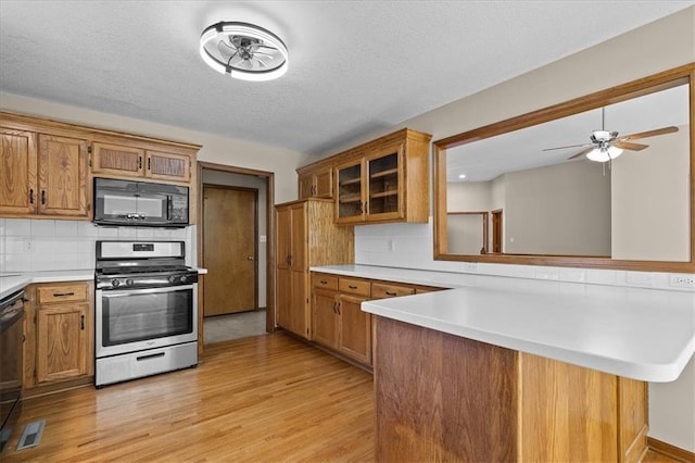 22716 E 29th Street Lane Ct S, Blue Springs, MO 64015 - kitchen with black microwave, stainless steel gas range oven, brown cabinets, light wood-style flooring, and a textured ceiling