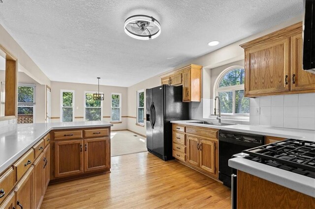 22716 E 29th Street Lane Ct S, Blue Springs, MO 64015 - kitchen featuring black appliances, a sink, a textured ceiling, light wood-style flooring, and plenty of natural light