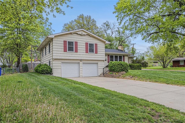 split level home with fence, an attached garage, a front lawn, a chimney, and concrete driveway