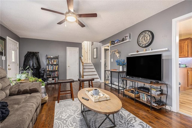 living area featuring stairs, a ceiling fan, a textured ceiling, and wood finished floors