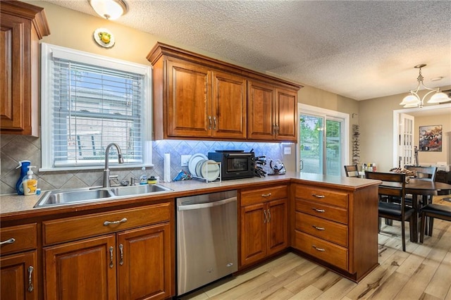 kitchen with stainless steel dishwasher, a sink, brown cabinets, and light wood-type flooring