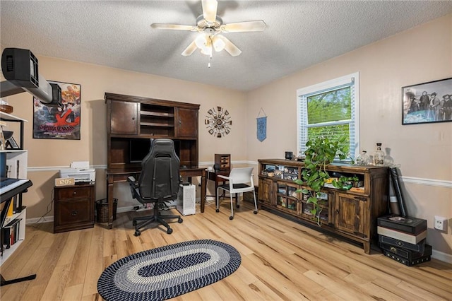 office space featuring a textured ceiling, ceiling fan, baseboards, and light wood-type flooring