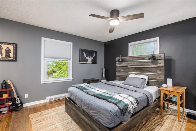 bedroom with visible vents, baseboards, ceiling fan, and wood finished floors