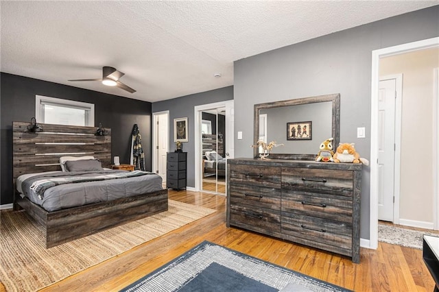 bedroom featuring baseboards, a ceiling fan, a textured ceiling, and wood finished floors