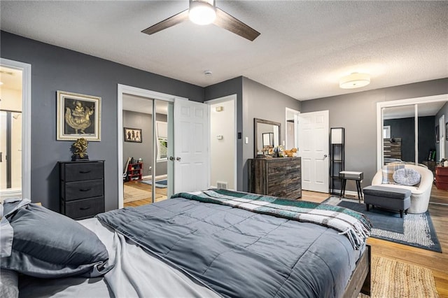 bedroom featuring ceiling fan, light wood finished floors, a textured ceiling, and visible vents