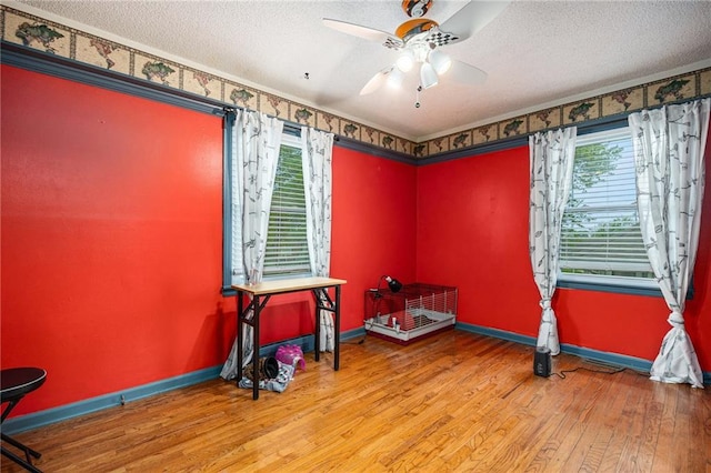 unfurnished room with a textured ceiling, baseboards, ceiling fan, and wood finished floors