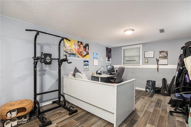office space featuring dark wood-style flooring, a textured ceiling, visible vents, and baseboards