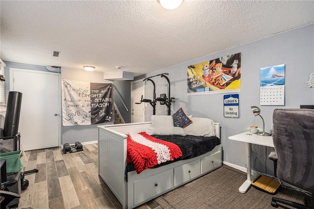 bedroom with visible vents, a textured ceiling, and wood finished floors