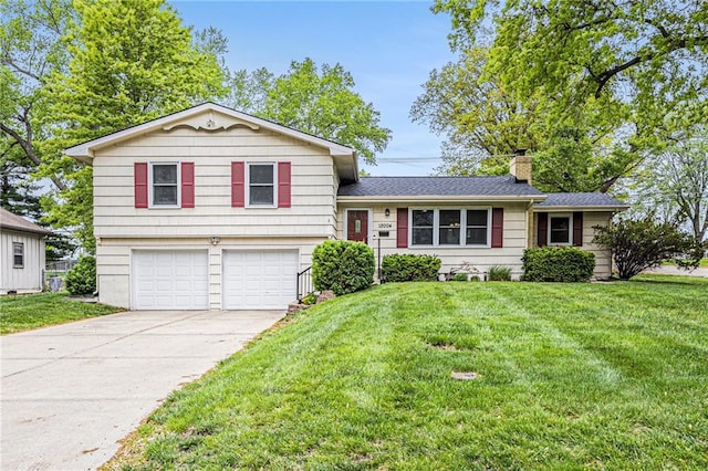tri-level home featuring concrete driveway, a chimney, an attached garage, and a front yard