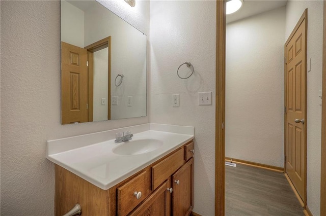 bathroom featuring a textured wall, wood finished floors, and vanity