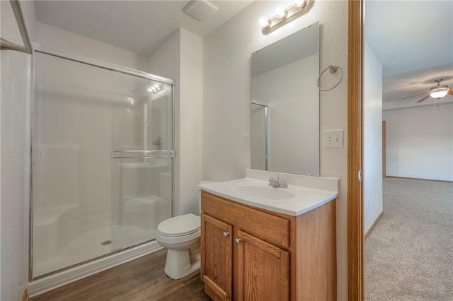 bathroom with toilet, a ceiling fan, a shower stall, and vanity