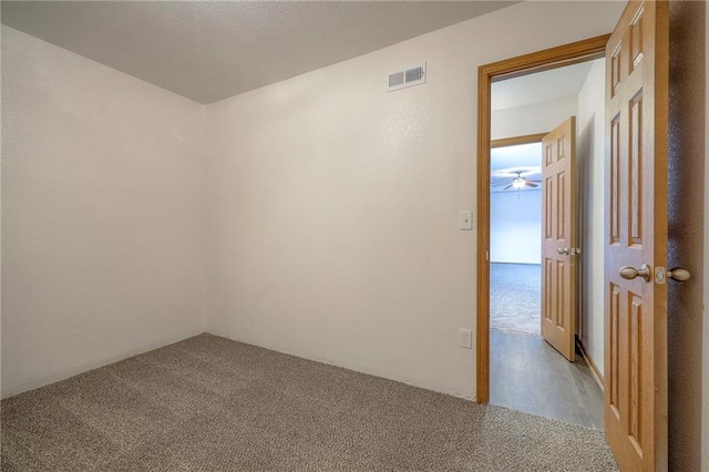 carpeted empty room featuring visible vents and ceiling fan