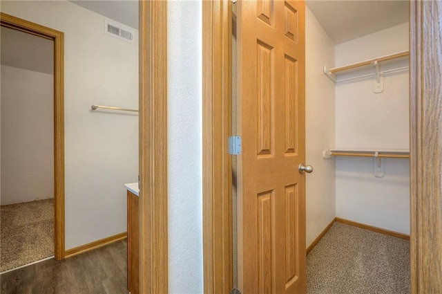 corridor featuring visible vents, carpet flooring, and baseboards