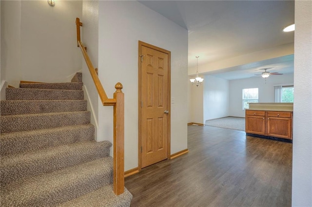 stairway with baseboards, ceiling fan with notable chandelier, and wood finished floors