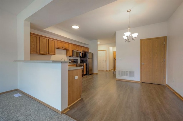 kitchen with electric range oven, brown cabinetry, a peninsula, stainless steel microwave, and visible vents
