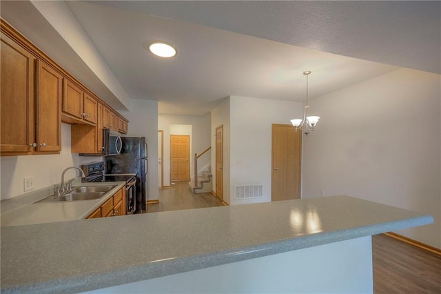 kitchen featuring visible vents, light wood-type flooring, brown cabinets, stainless steel microwave, and electric stove