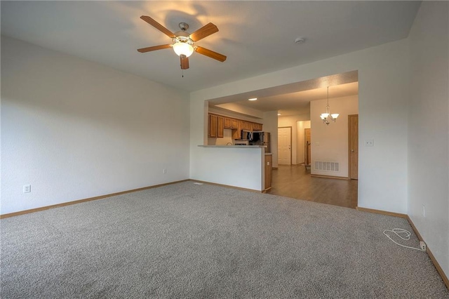 unfurnished living room with baseboards, visible vents, carpet, and ceiling fan with notable chandelier