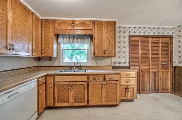 kitchen with white dishwasher, light countertops, a sink, ornamental molding, and wallpapered walls