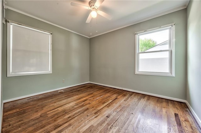 spare room featuring crown molding, baseboards, ceiling fan, and wood finished floors