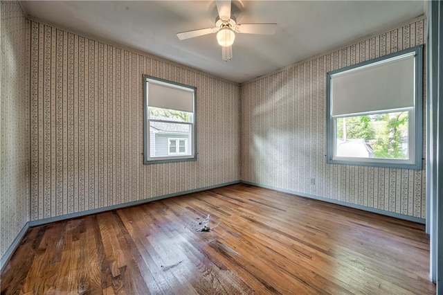 unfurnished room with baseboards, a ceiling fan, wallpapered walls, and hardwood / wood-style floors