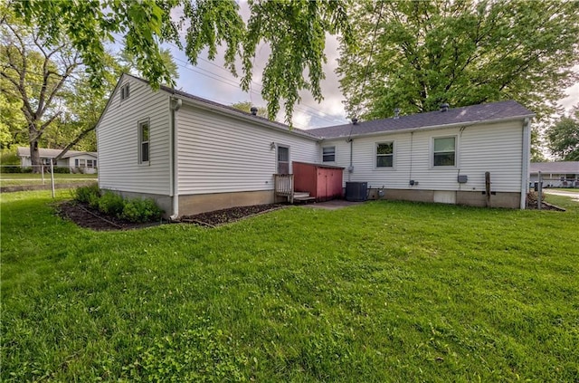 rear view of property with central AC unit and a yard