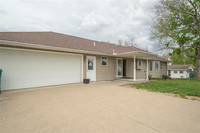 ranch-style home featuring a garage, a front lawn, roof with shingles, and concrete driveway