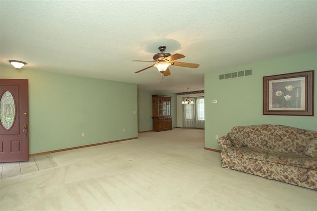 unfurnished living room featuring carpet flooring, a ceiling fan, visible vents, baseboards, and a textured ceiling