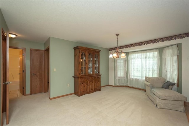 unfurnished room with light carpet, baseboards, an inviting chandelier, and a textured ceiling