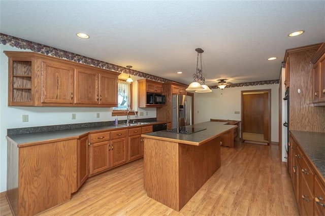 kitchen with black appliances, dark countertops, a sink, and a kitchen island