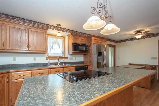 kitchen featuring dark countertops, a sink, brown cabinetry, and black appliances