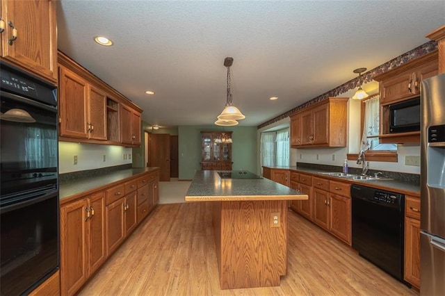 kitchen featuring black appliances, dark countertops, and a sink