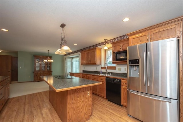 kitchen featuring black appliances, dark countertops, light wood-style floors, and a sink