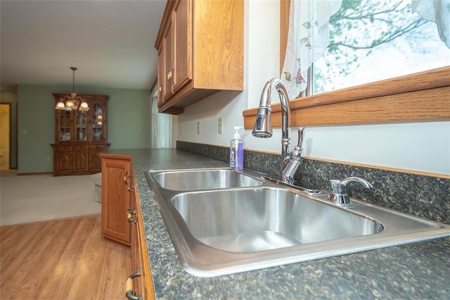 interior details with brown cabinetry, hanging light fixtures, a sink, and light wood-style floors