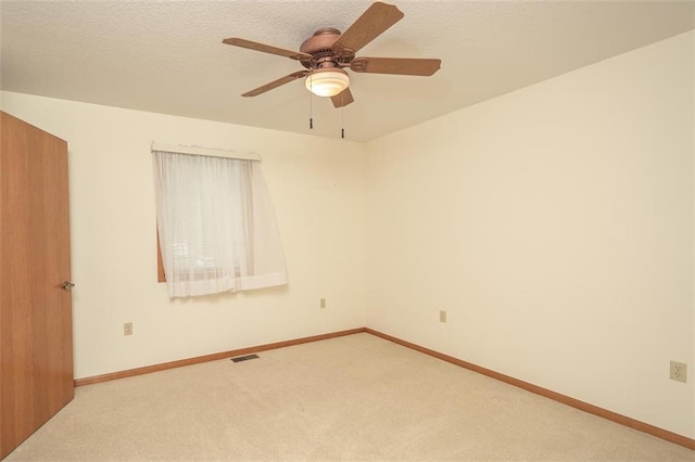 empty room featuring a textured ceiling, ceiling fan, carpet, baseboards, and visible vents