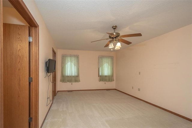empty room with baseboards, a textured ceiling, light colored carpet, and ceiling fan