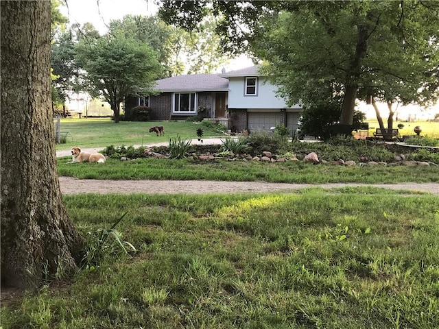 tri-level home featuring a garage, brick siding, and a front lawn