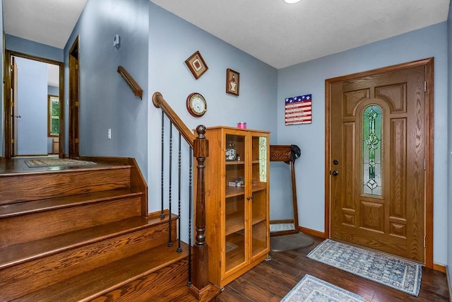 foyer with dark wood-style flooring, baseboards, and stairway