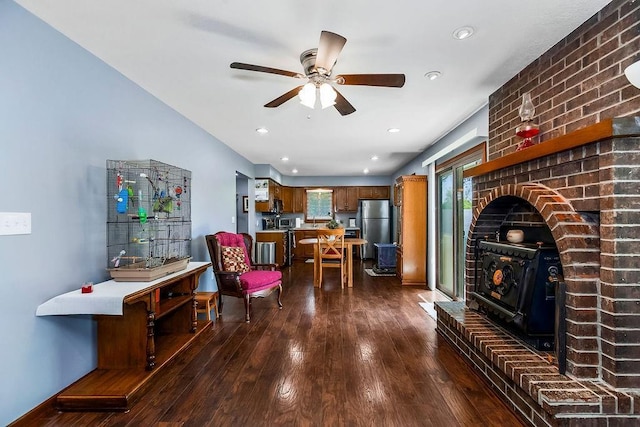 living area featuring a wood stove, dark wood finished floors, ceiling fan, and recessed lighting