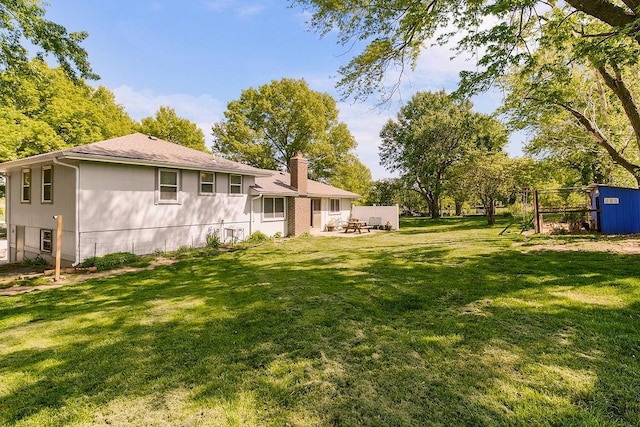 back of property featuring a chimney, a lawn, and a patio area