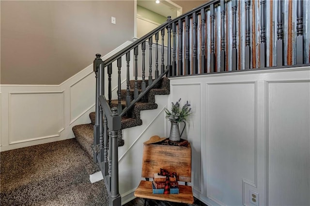 stairway with wainscoting and a decorative wall