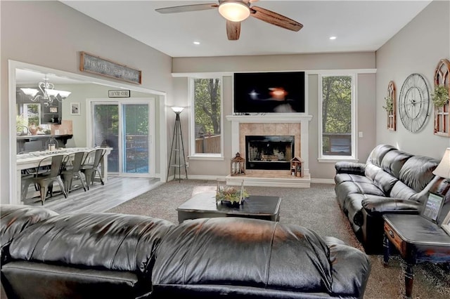 living room with plenty of natural light, recessed lighting, ceiling fan with notable chandelier, and a tile fireplace
