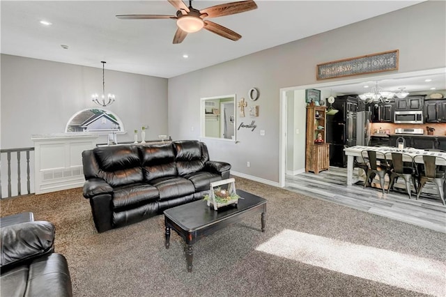 living room with baseboards, light carpet, ceiling fan with notable chandelier, and recessed lighting