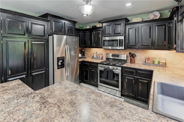 kitchen featuring dark cabinetry, appliances with stainless steel finishes, and decorative backsplash