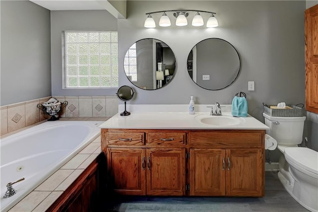 bathroom featuring a jetted tub, vanity, and toilet