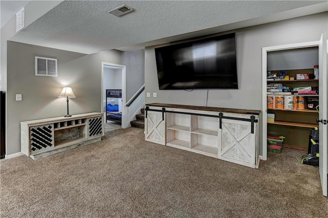 living area with carpet flooring, stairs, a textured ceiling, and visible vents