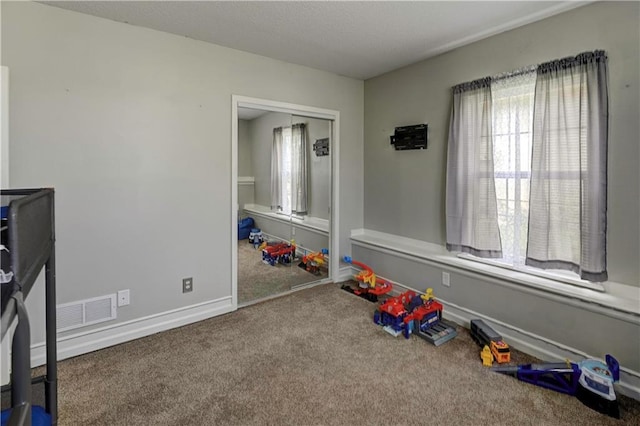 playroom with carpet floors, baseboards, and visible vents