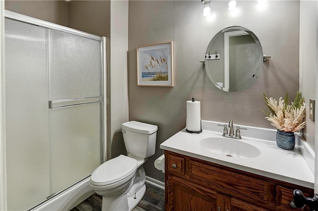 full bath featuring vanity, toilet, baseboards, and a stall shower