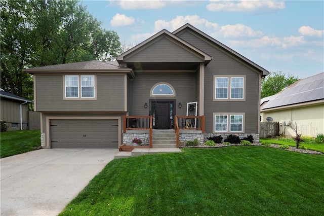 bi-level home with stone siding, an attached garage, driveway, and a front yard